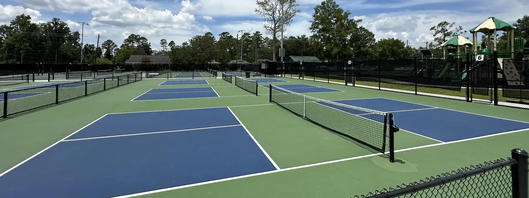 Row of outdoor pickleball courts with blue and green acrylic hard court surface