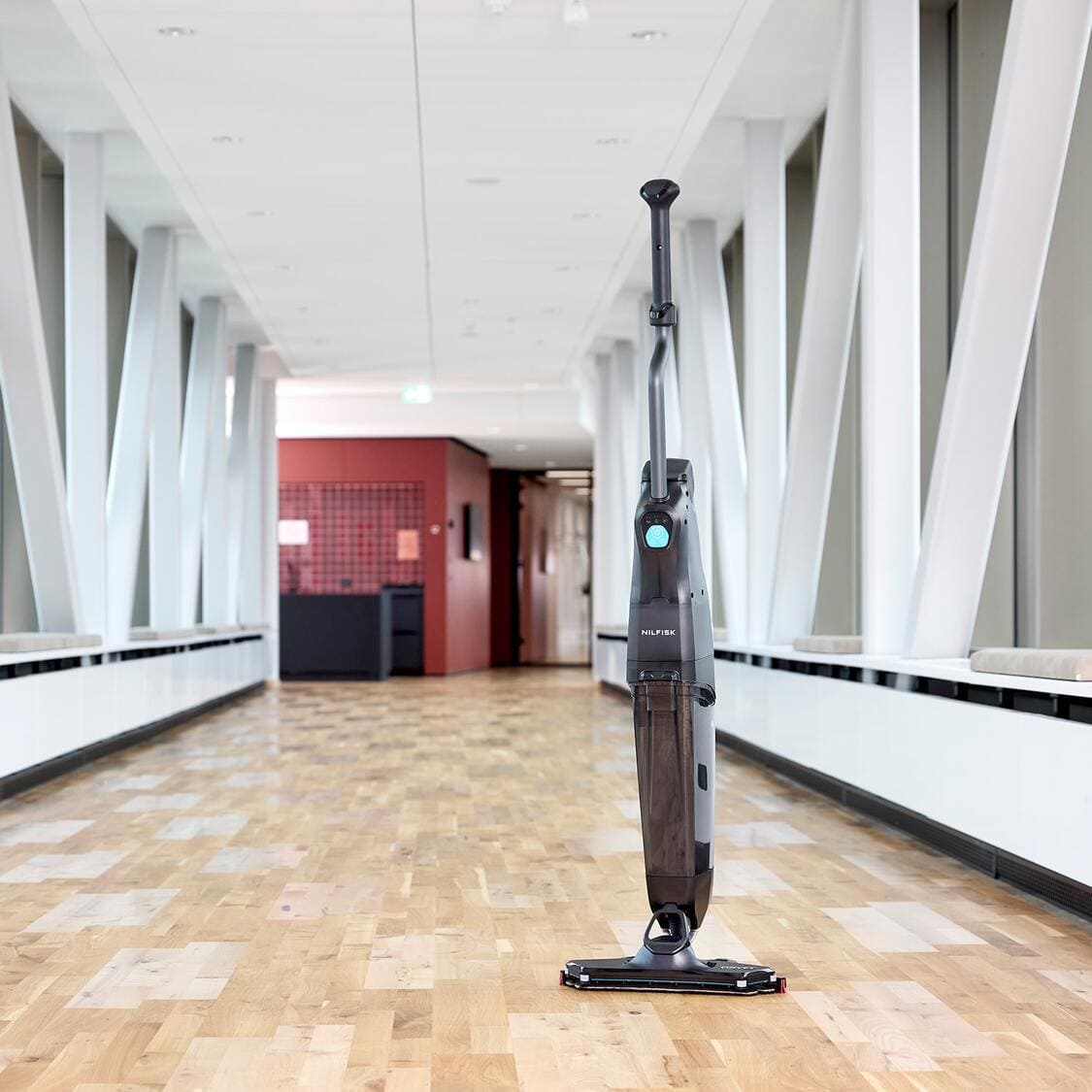 Nilfisk Dryft Floor Scrubber Hero Image viewed from a front left angle, in a corridor with wooden hard floors