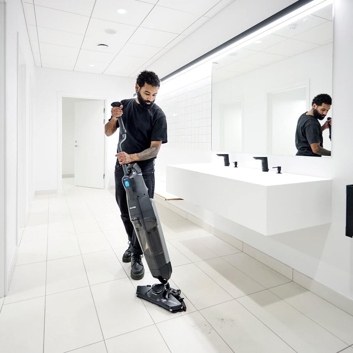 Nilfisk Dryft Floor Scrubber in use cleaning restroom by operator