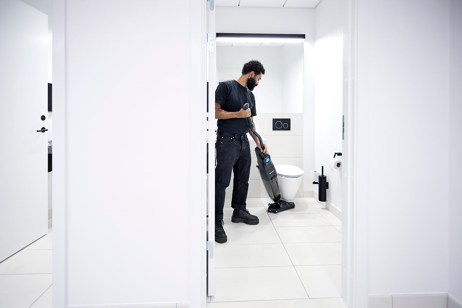 Nilfisk Dryft Floor Scrubber in use cleaning bathroom floors by janitor