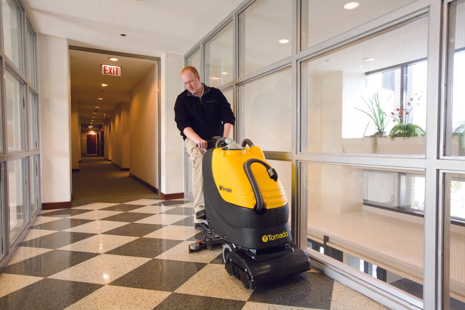Tornado BR 18/11 Automatic Scrubber In Use by Operator in a Hallway Space