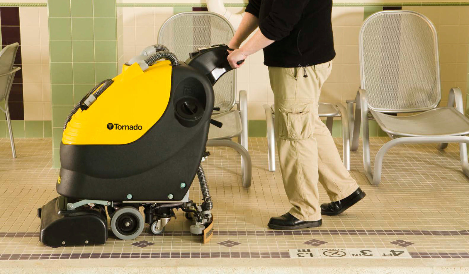 Tornado BR 18/11 Automatic Scrubber In Operation in a Poolside Space - Left Side View Being Pushed by User