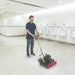 Operator scrubbing a tiled restroom floor with a Clarke FM40 LX orbital floor machine