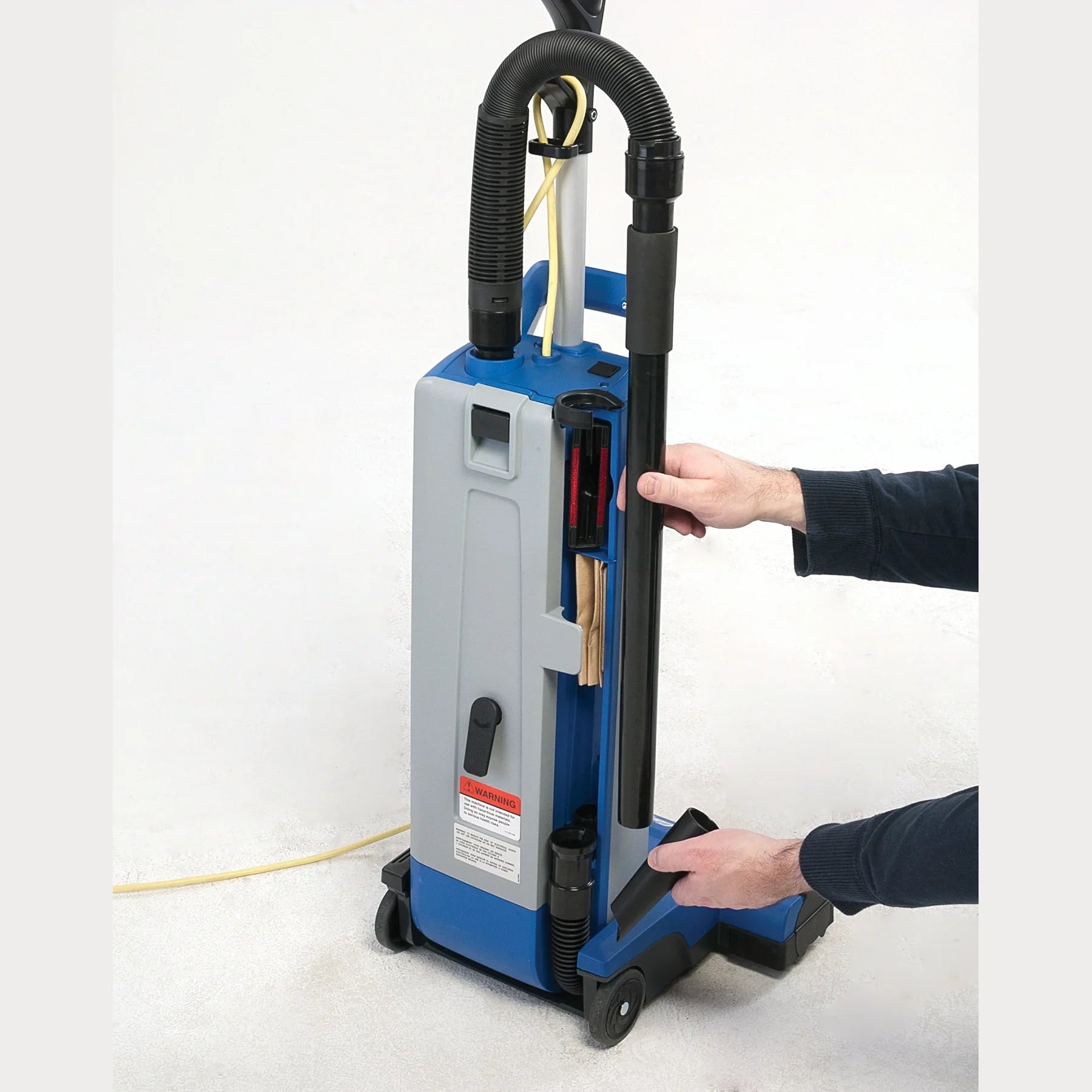 Onboard crevice and upholstery tools being taken from behind the wand of a Clarke CarpetMaster 115