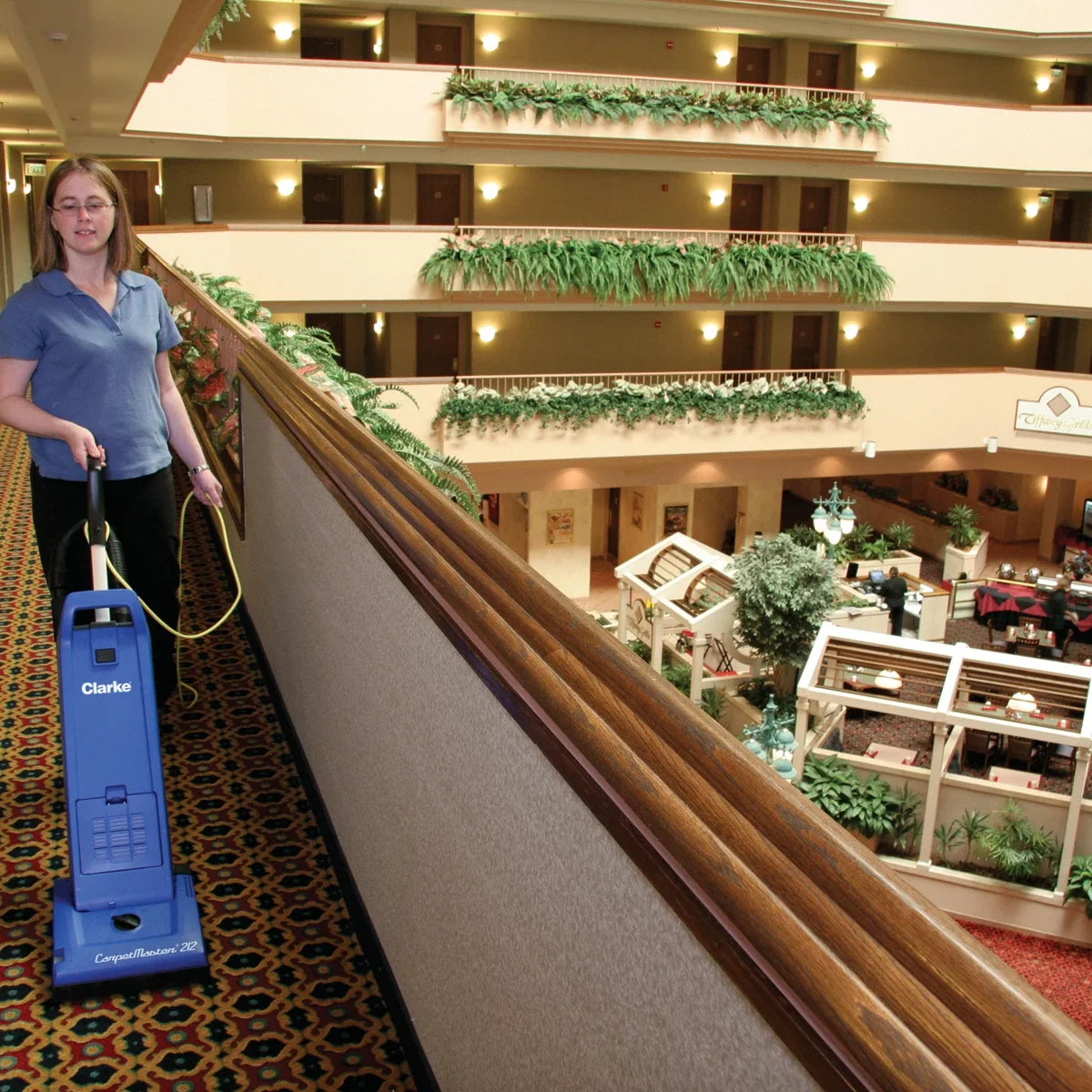 Housekeeper vacuuming a hotel atrium walkway with a Clarke CarpetMaster 212