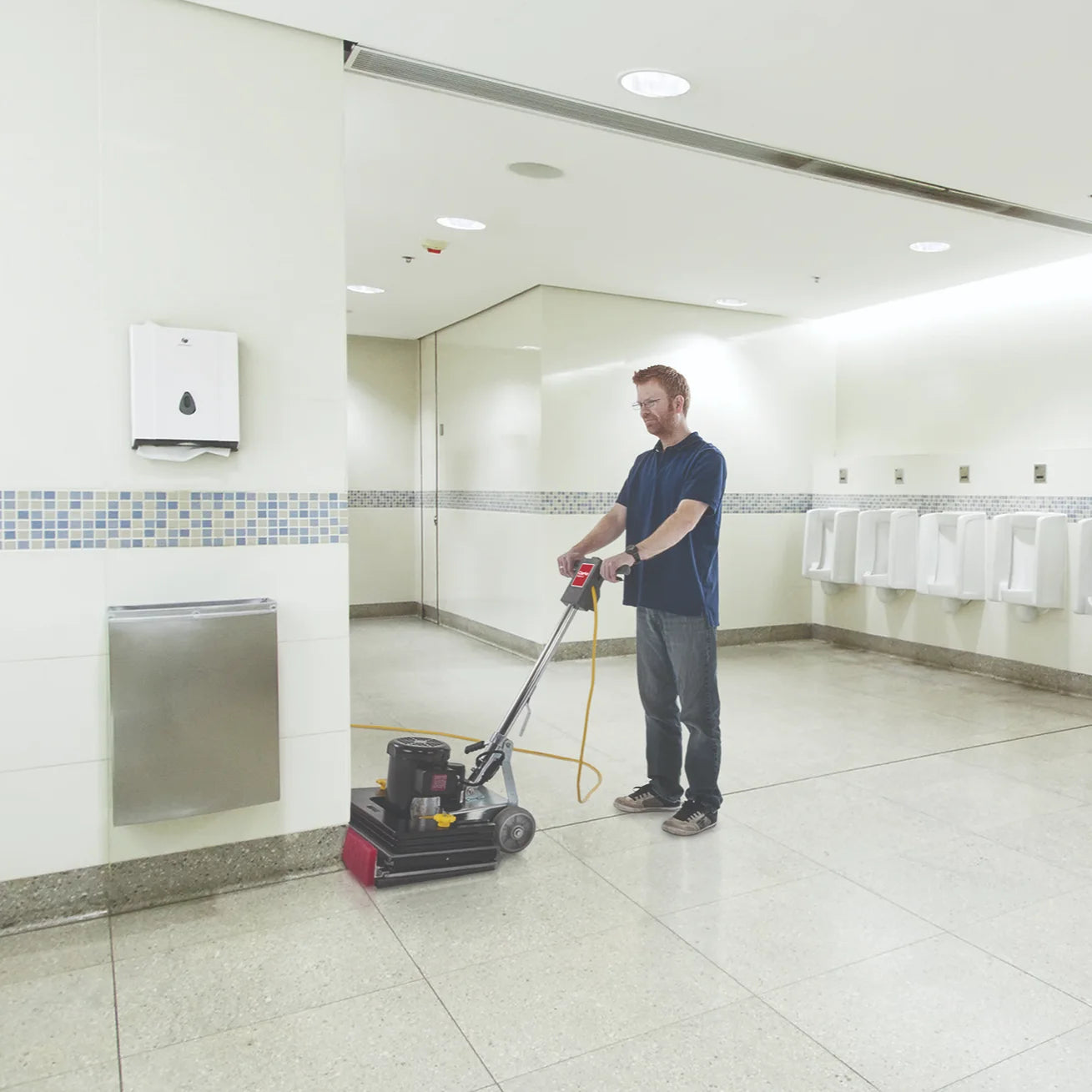 Clarke FM40 LX scrubbing a restroom floor along the wall with the baseboard cleaner
