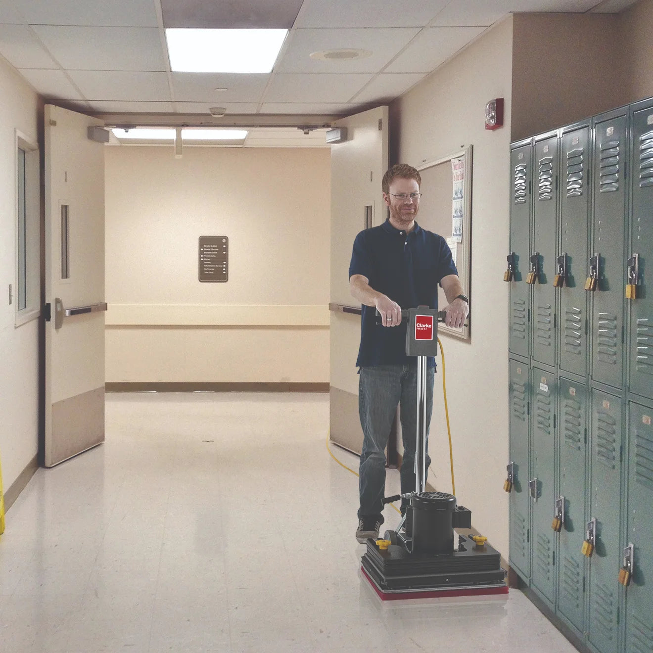 Operator with the Clarke FM40 ST orbital floor machine in a school hallway
