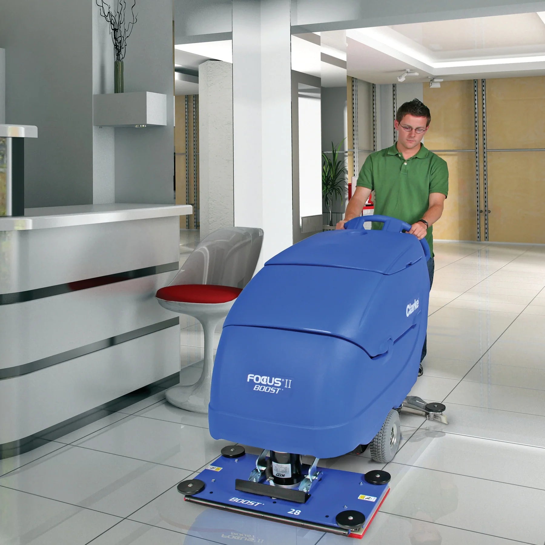 Operator pushing a Clarke Focus II BOOST 28 scrubber across a tile floor in a modern office