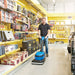 Operator cleaning a store floor between tool shelves with the Clarke MA30 13B micro scrubber