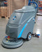 ICE i18C floor scrubber parked on a sealed concrete warehouse floor next to stacked pallets and boxes