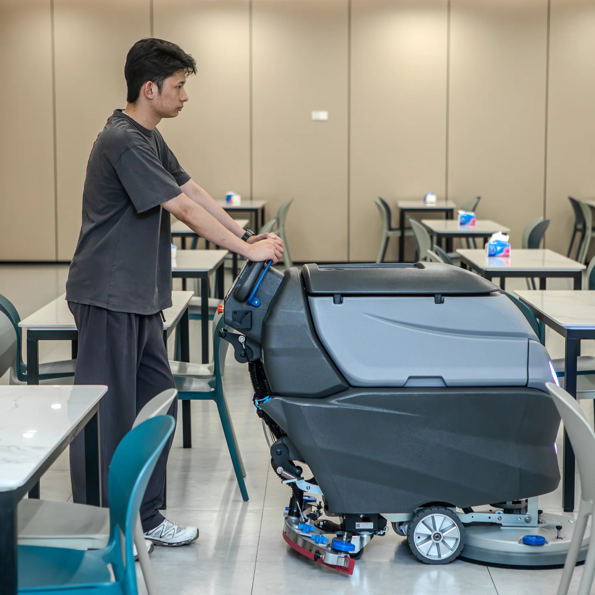Operator scrubbing a tiled floor between tables and chairs with the ICE i20YT