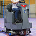 Operator driving an ICE ride-on floor scrubber across a large indoor floor