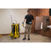 Custodian in gloves rinsing a tiled restroom floor with the KaiVac 1250 spray gun, machine parked beside him