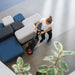 Overhead view of an operator steering the 220NX around lobby sofas on a gray tile floor