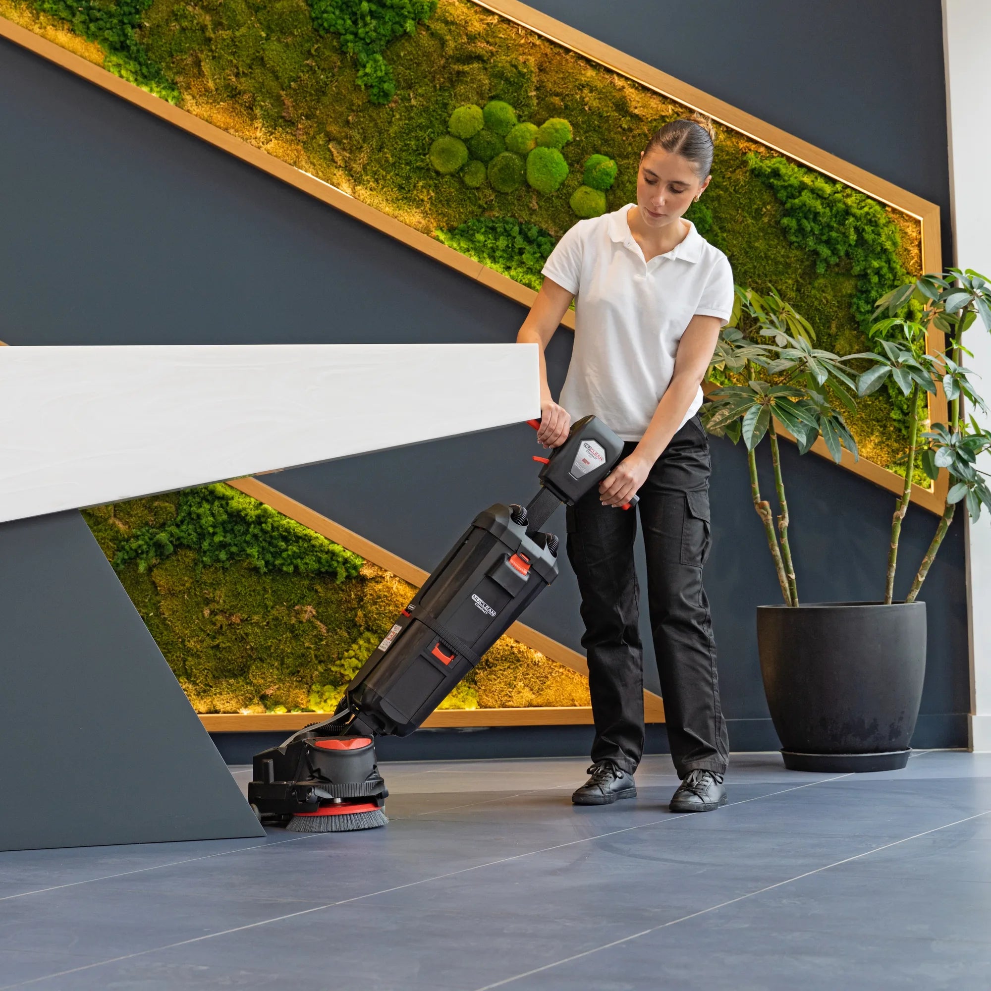 NaceCare 220NX cleaning the tile floor tight against the base of an office reception desk