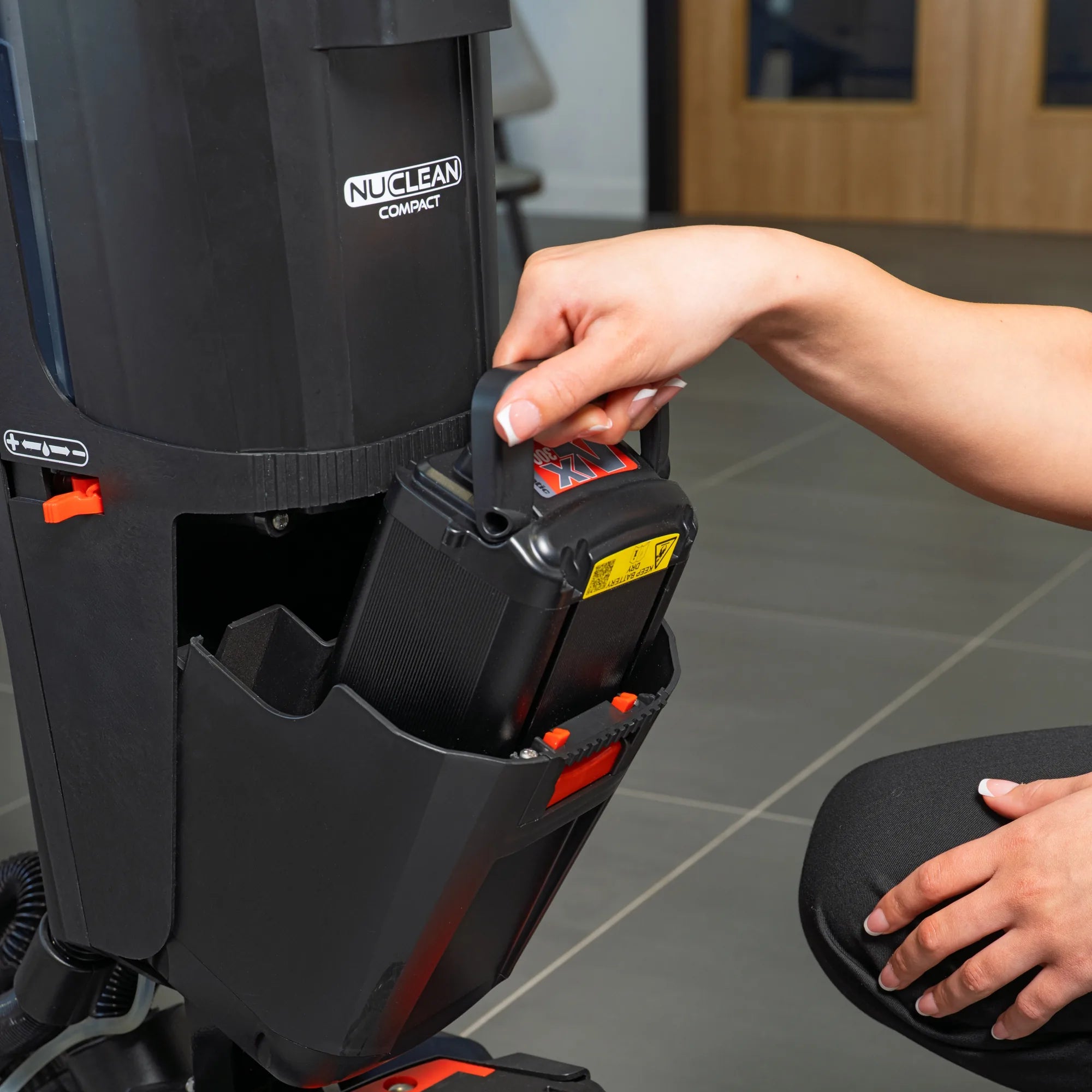 Hand lifting the NX300 lithium battery out of its slot on the NaceCare 220NX by the carry handle