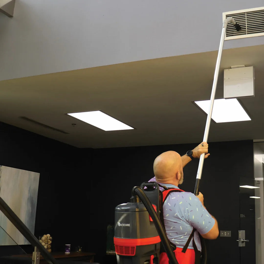Worker using the NaceCare high-level dusting kit to clean a ceiling