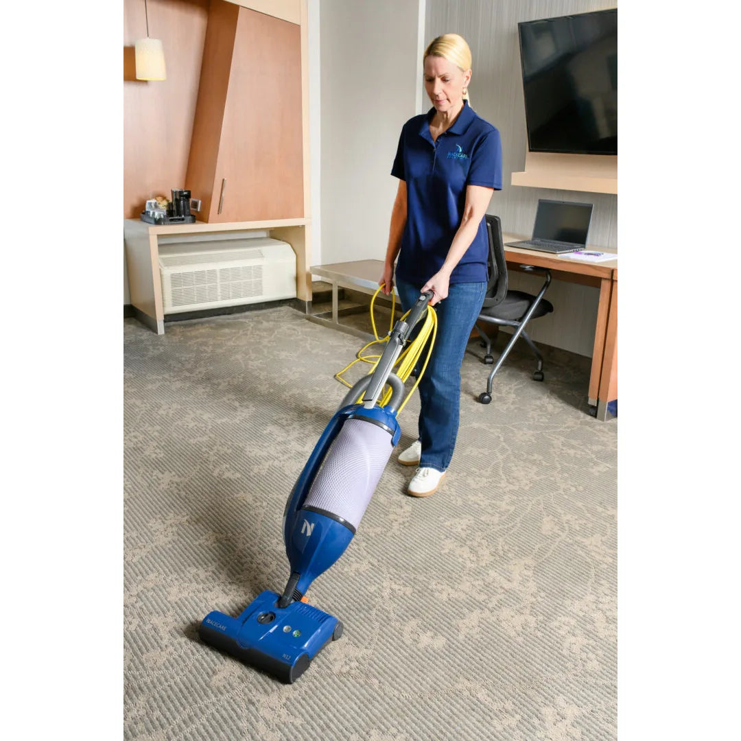 Housekeeper vacuuming hotel room carpet with the NaceCare upright