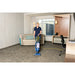 Housekeeper vacuuming a hotel room carpet with a NaceCare upright vacuum