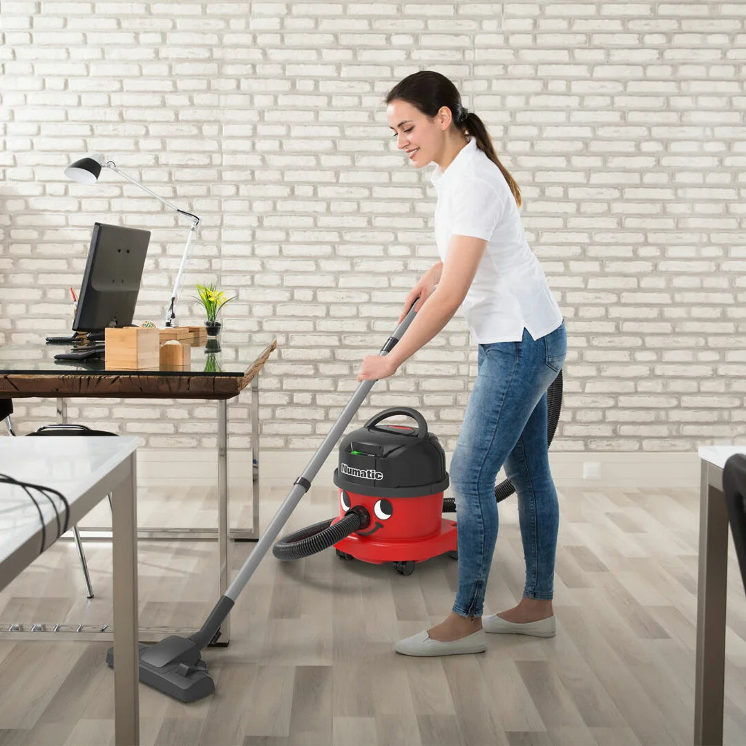 Cleaner vacuuming an office hard floor with the cordless NBV 240NX