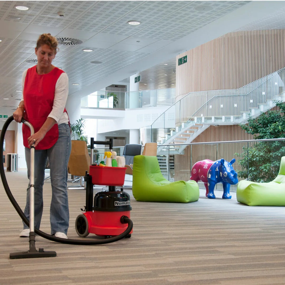 Custodian vacuuming carpet in a modern office lounge with the cordless NBV 290NX