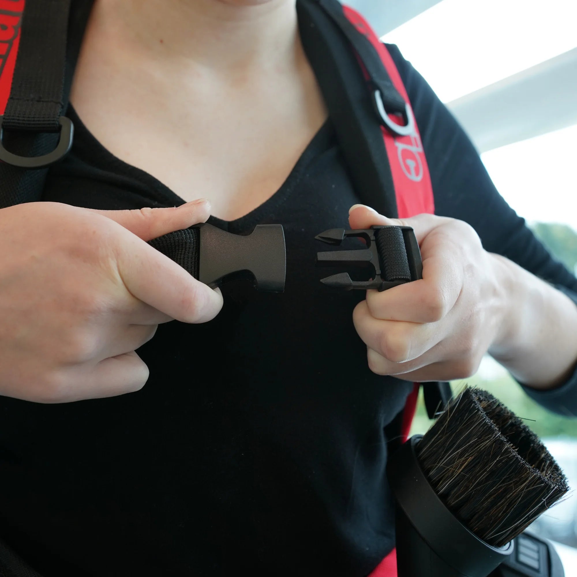 Clipping the chest buckle on the NaceCare RBV 150NX backpack vacuum harness