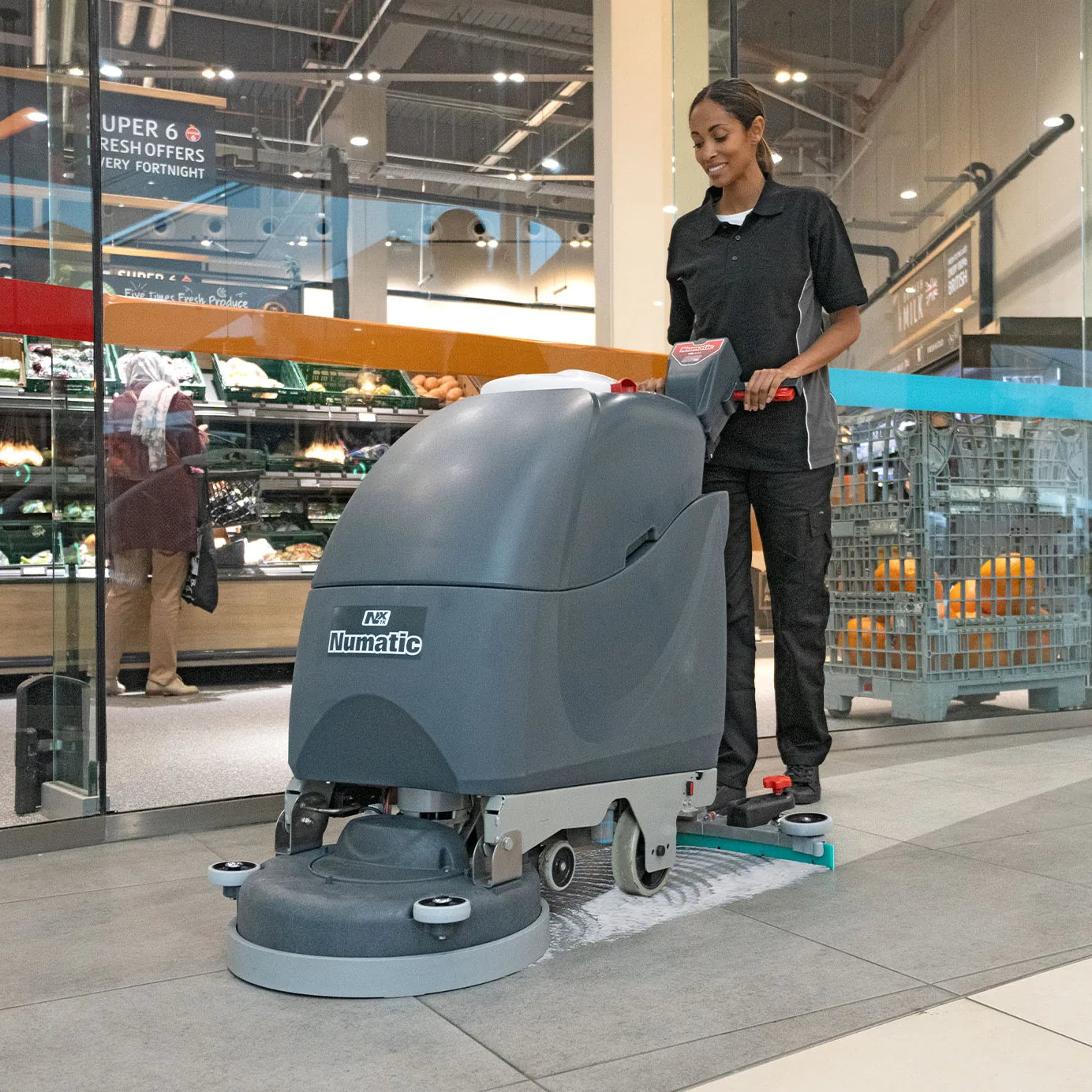 Operator scrubbing a grocery store floor near the entrance with the NaceCare TBL 1120