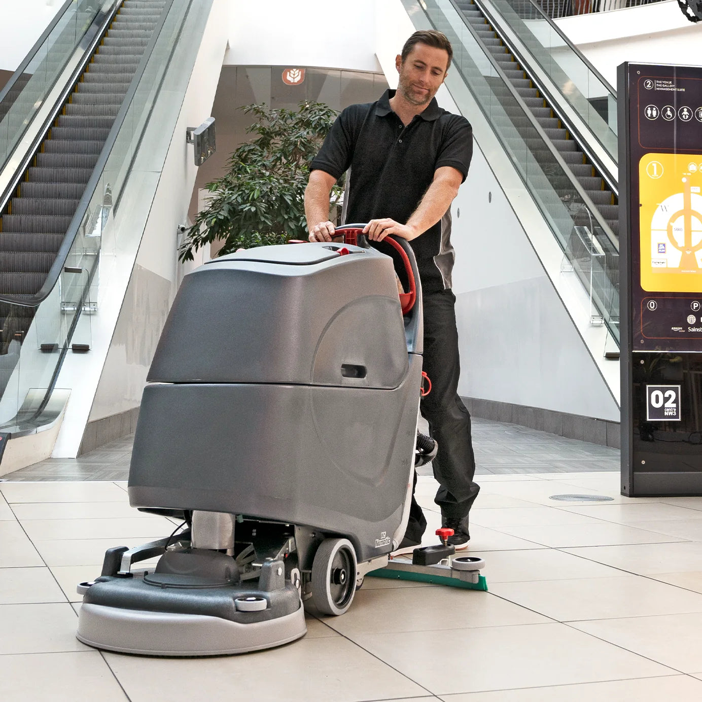Operator scrubbing a transit concourse near the escalators with the NaceCare TBL 1620T