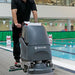 Custodian running the NaceCare TGB 817NX on a pool deck at an indoor aquatic center