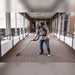 Cleaner vacuuming a carpeted glass walkway with a Comfort Pro backpack vacuum