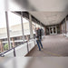 Cleaner reaching high along a glass walkway with the wand of a Comfort Pro backpack vacuum