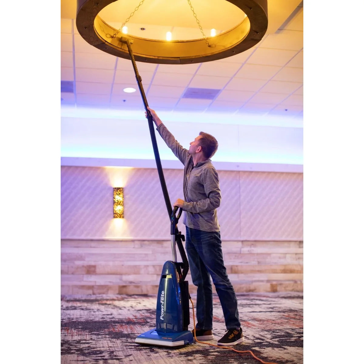 Cleaner dusting a hotel lobby ceiling light with the Rigel Pro's hose and telescopic wand