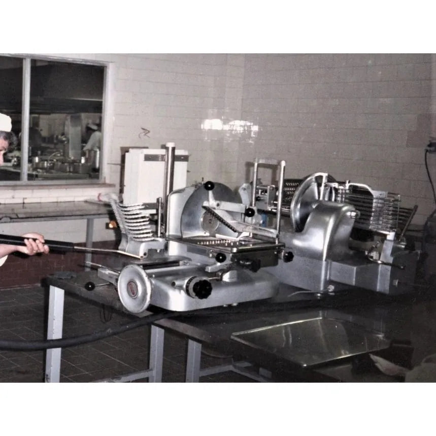 Operator steam cleaning commercial meat slicers in a food plant with a Therma-Steem industrial dry vapor steam cleaner
