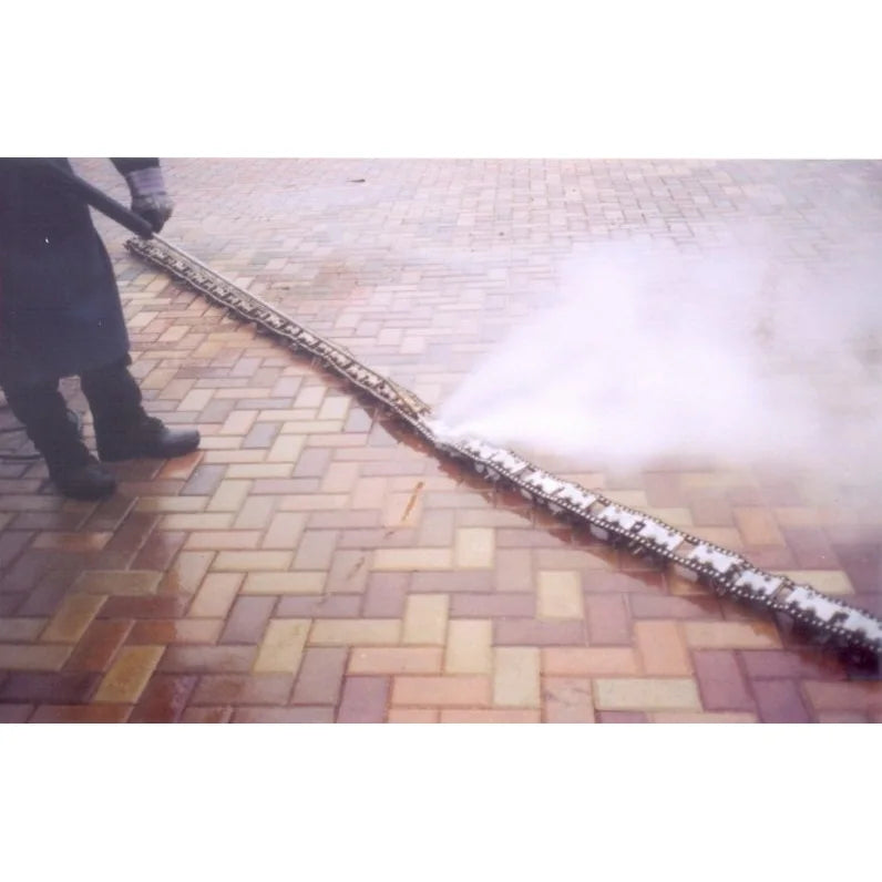 Operator cleaning red brick pavers with a high-pressure steam bar, steam rising from the cleaned strip