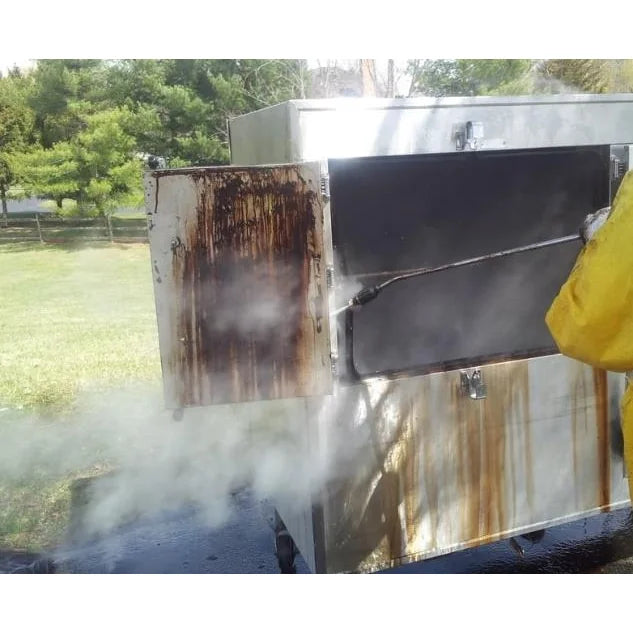 Steam cleaning the greasy interior of a commercial smoker oven outdoors with a long wand