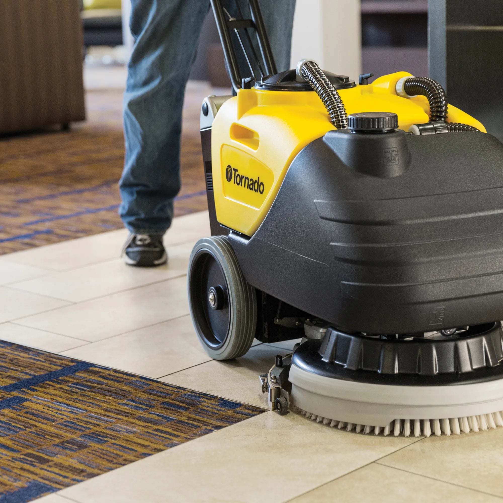 Tornado BD 17/6 compact scrubber scrubbing a tile floor in a hotel lobby