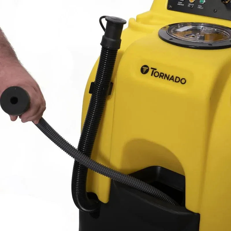 Operator holding the hose beside the top control panel of a Tornado Surge carpet extractor, with the pump, heater and vacuum switches and the pressure regulator