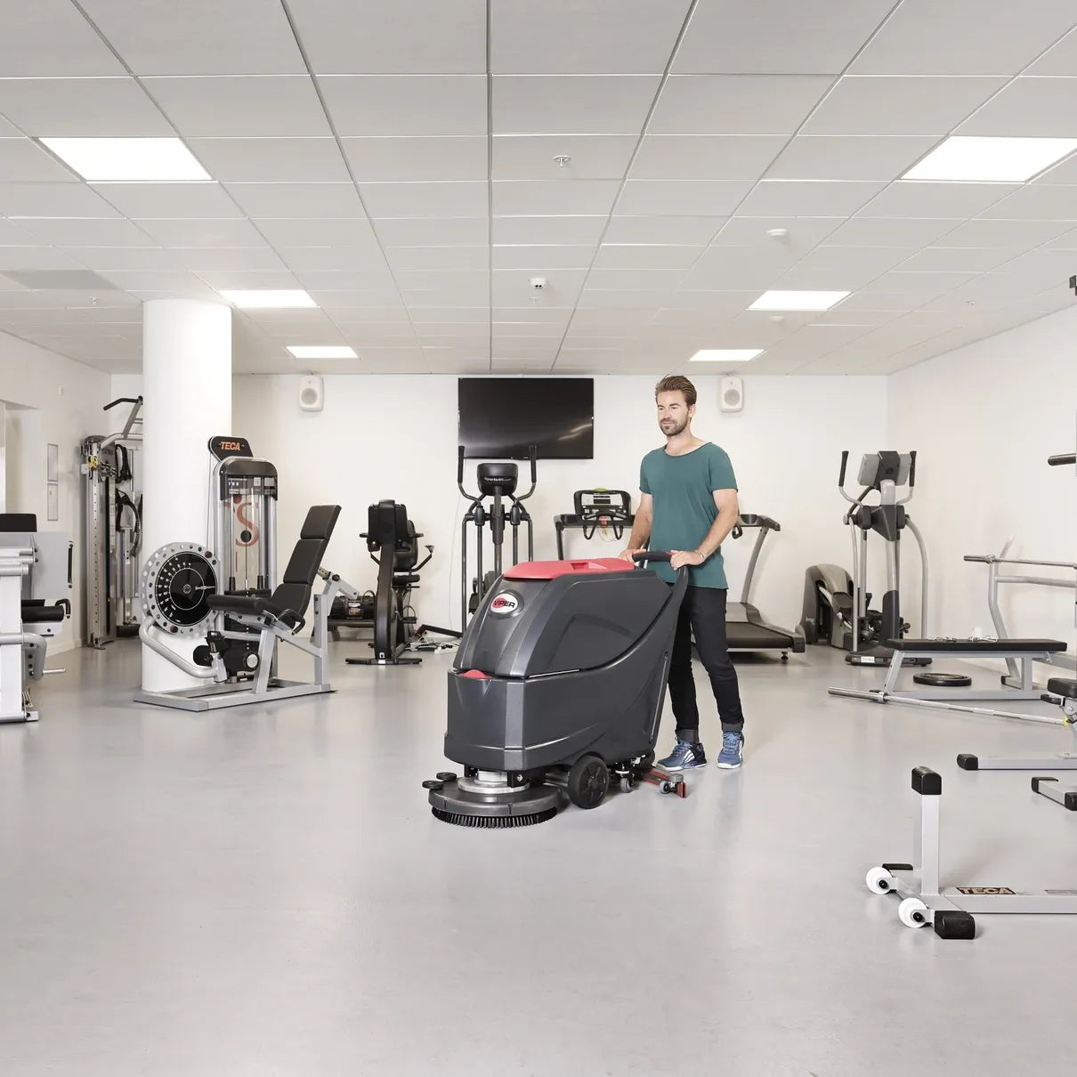 Viper AS5160 walk-behind scrubber cleaning the floor of a fitness center between weight machines