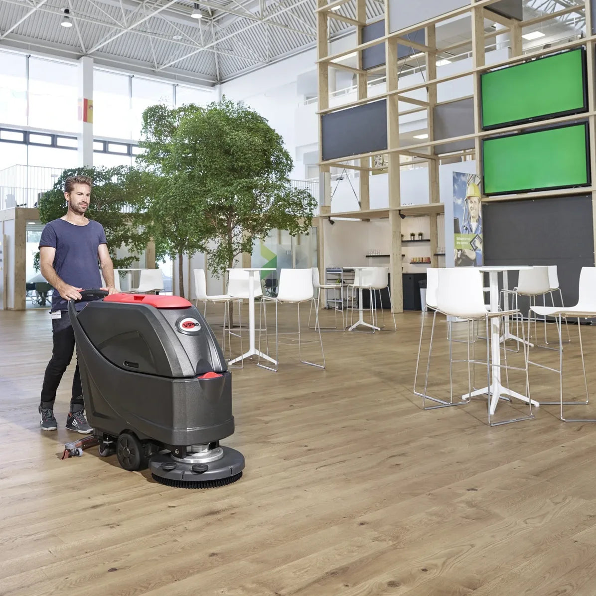 Viper AS5160 series walk-behind scrubber cleaning an open hall floor next to a seating area with tables and chairs