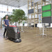 Viper AS5160 series walk-behind scrubber cleaning an open hall floor next to a seating area with tables and chairs