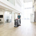 Operator guiding the Viper AS5160T floor scrubber across a light wood-look floor in a bright office atrium