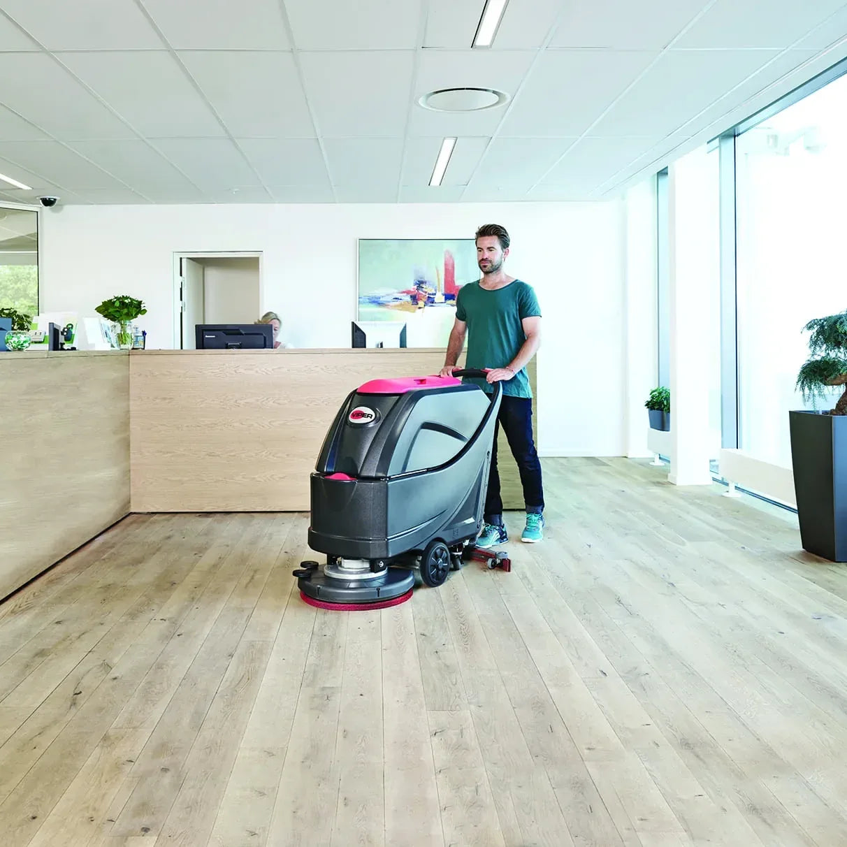 Operator running the Viper AS5160T with a pad driver across a wood-look reception area floor
